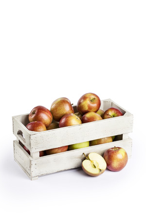 Fresh apples in a wooden crate on white backgroundの写真素材