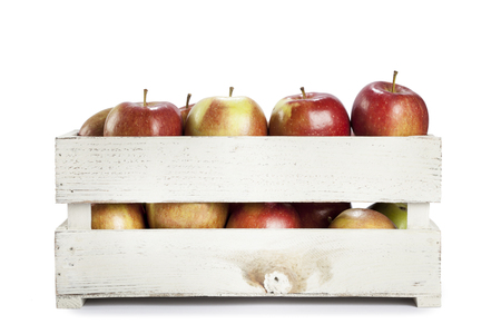 Fresh apples in a wooden crate on white backgroundの写真素材