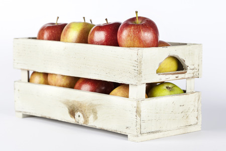 Fresh apples in a wooden crate on white backgroundの写真素材