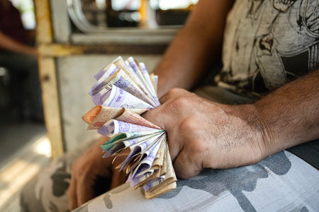 Bus conductor in Kolkata holding Indian rupee notes while collecting fares.の写真素材