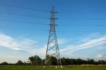 High voltage pylon in paddy with blue sky and clouds