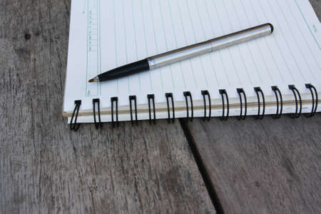 spiral notebook and pen on wooden deskの写真素材
