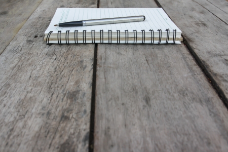 spiral notebook and pen on wooden deskの写真素材