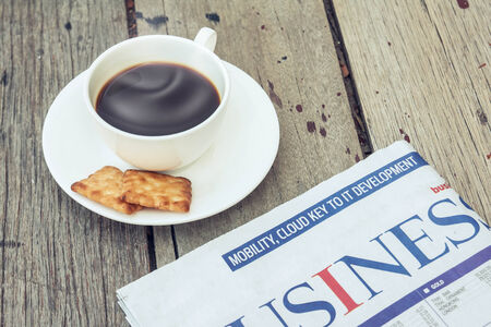 Cup of coffee with crackers and newspaper on woodenの写真素材