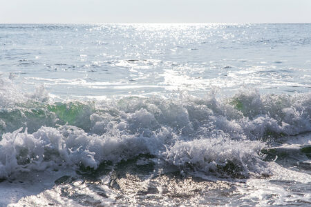 sand sea beach and blue sky after sunrise and splash of seawater with sea foam and waves