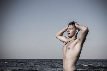 Attractive young man in the sea getting out of water with wet hairの写真素材