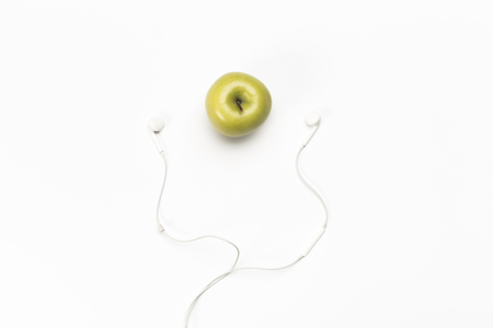 single green color apple and digital audio headphones isolated on white backgroundの写真素材