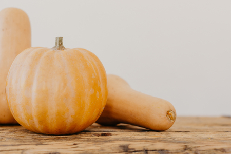 Bright yellow and orange pumpkins on light brown wooden table, text spaceの写真素材