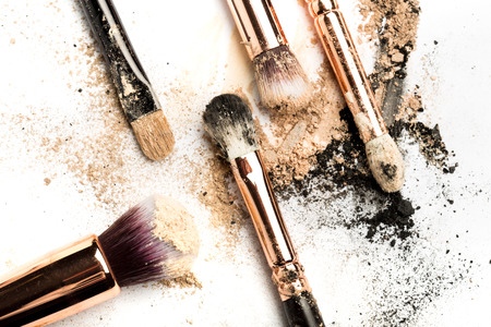 Close-up side view of professional make-up brush with natural bristle and black ferrule with crashed eyeshadow isolated on white backgroundの写真素材