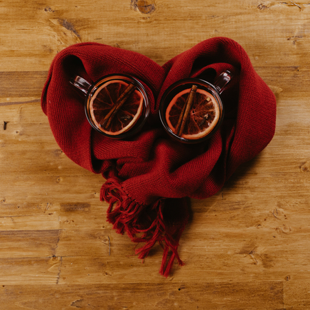 Decorated composition of mugs with mulled wine in knitted scarf, close upの写真素材