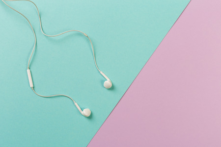 White earphones on colour background