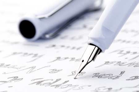 yellow and white fountain pens on a letterの写真素材