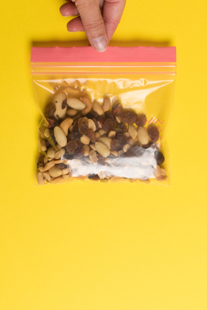 Plastic zip package for food storage. Healthy snack nuts in a closed package on yellow backgroundの写真素材