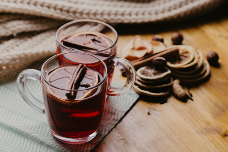 Decorated composition of mugs with mulled wine in knitted scarf, close up.の写真素材