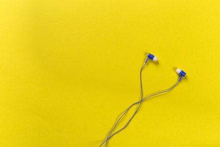 black earphones on colour background, top view