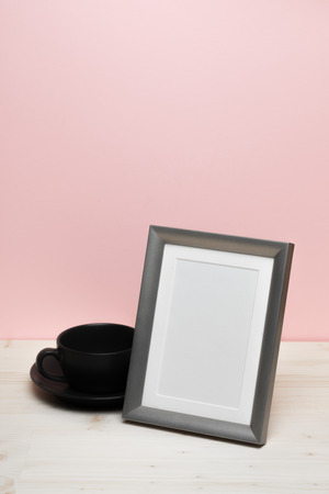 silver frame with mug on white desk near pink wallの写真素材
