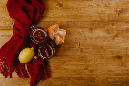 Mulled wine in mugs with scarf on wooden tableの写真素材