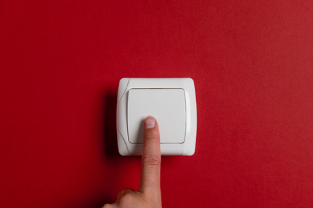 finger press light switch on a bright red background