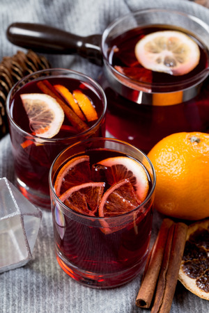 Mulled wine in glasses with orange and spices with gray scarfの写真素材