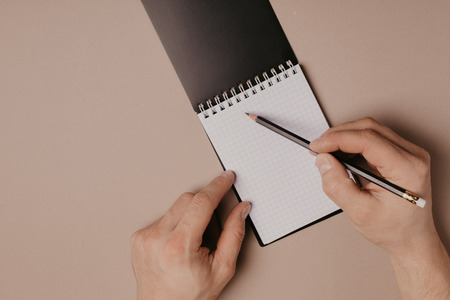 Hand writing in notepad using a pencil, on gray backgroundの写真素材