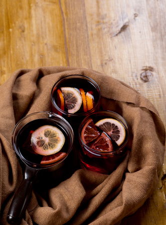 Seasonal and holidays concept Christmas mulled wine with beautiful orange slices inside the glass , covered with warm white scarf . Very warm and cozy atmosphere .Copy space.Top view.の写真素材