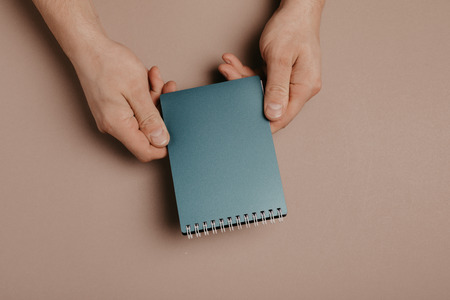 hand holding notebook on gray background