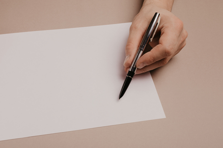 Hands writing on paper blank a4 size on grey background.の写真素材