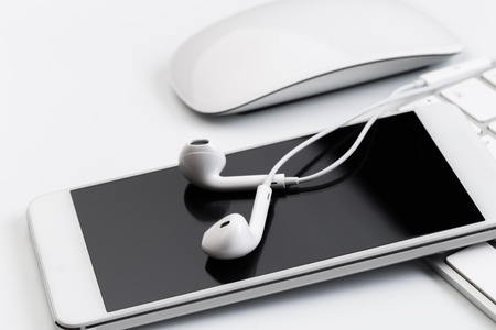 white earphones on white keyboard with phoneの写真素材