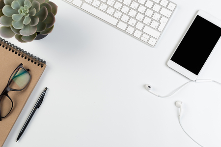 Top View of trendy White Office Desk with keyboard, white earphones and office suppliesの写真素材