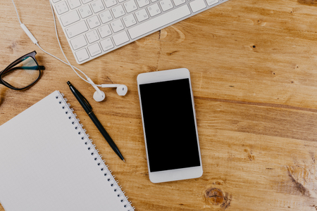 Top View of trendy wooden Office Desk with keyboard, white earphones and office suppliesの写真素材