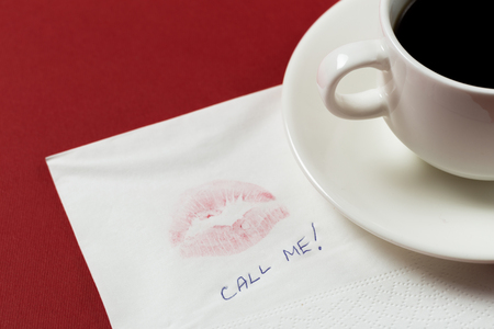 Napkin with a kiss and coffee cup on red backgroundの写真素材