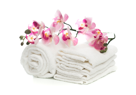 Stack of clean soft towels with orchid flower on white backgroundの写真素材