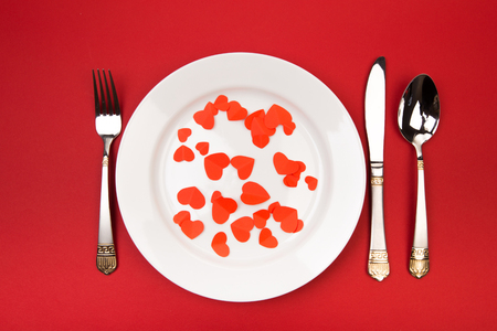 Festive table setting for Valentine's Day with fork, knife,  hearts on a red background. Top view. - Imageの写真素材