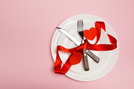 Festive table setting for Valentine's Day with fork, knife,  hearts on a red background. Top view. - Imageの写真素材