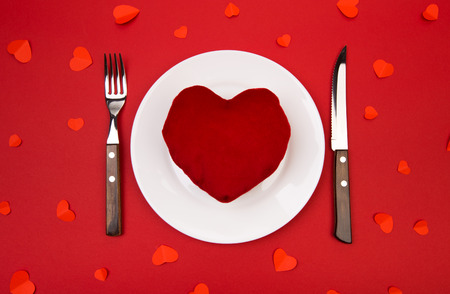 Heart on a plate for dinner. A romantic evening with hearts on red backgroundの写真素材