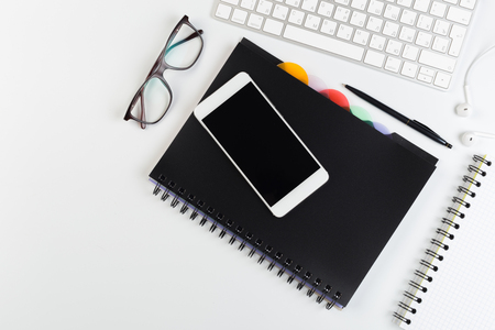 Top View of trendy White Office Desk with keyboard, white earphones and office suppliesの写真素材