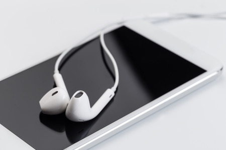 white earphones on white keyboard with phoneの写真素材