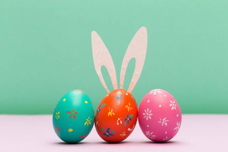 easter eggs with bunny ears on colour background