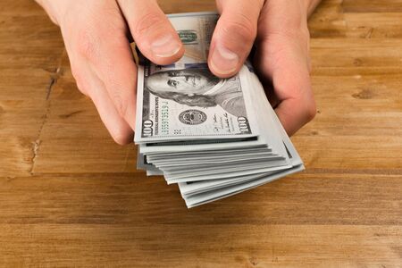 Man count the new us dollars on wooden table