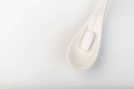 spoon with white tablets on white background- IMAGEの写真素材