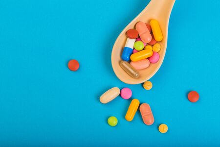 Colorful medical pills on spoon and capsules or supplements for therapy in background, concept of treatment and health care - Imageの写真素材