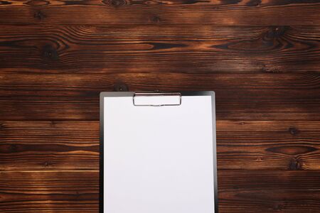 Clipboard with white sheet on wood background. Top view. - Imageの写真素材