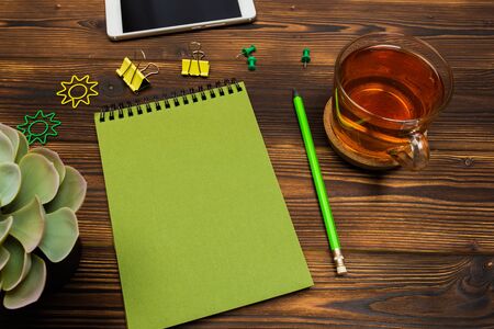 Top view business office desk.notebook,pencil,tea cup ,plant ,mobile phone,paperclips on wooden table background. - Imageの写真素材