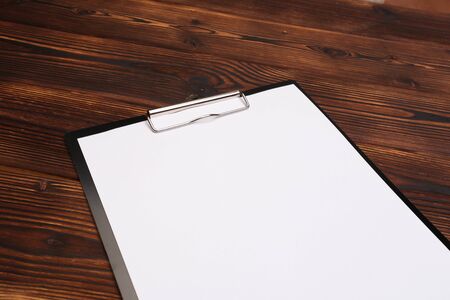 Clipboard with white sheet on wood background. Top view. - Image