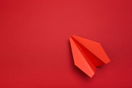 Flat lay of red paper plane on red background with text space. - Image