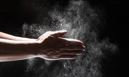 Powdery flour flying into air as man in black chef outfit wipes off his hands  - Imageの写真素材