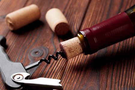 Corkscrew and bottle of wine on the boardの写真素材