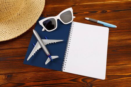 Travel vacation background concept with notebook, sun hat, phone, passport, airplane toy on wooden background - Imageの写真素材