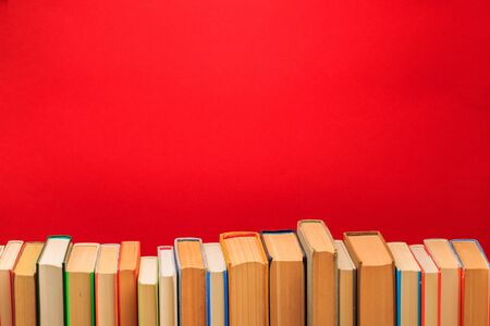Simple composition of hardback books, raw of books on wooden deck table and red background - Imageの写真素材