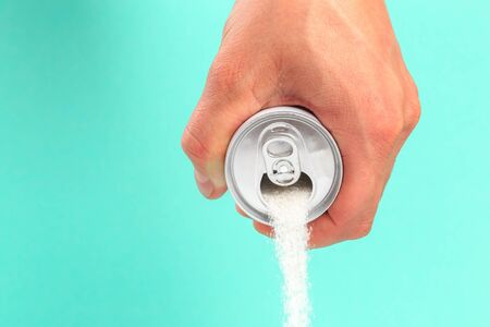 hand holding soda can pouring a crazy amount of sugar in metaphor of sugar content of a refresh...